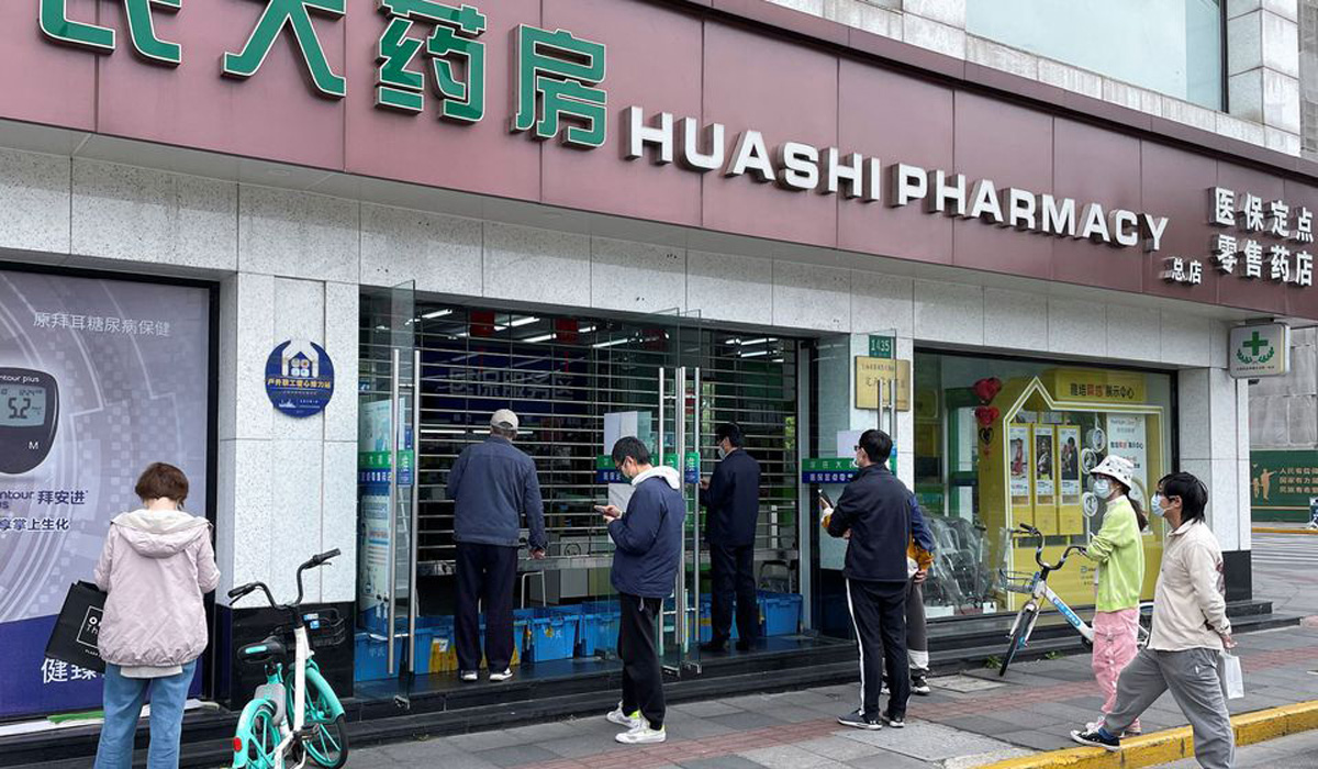 People wait outside a pharmacy to buy products